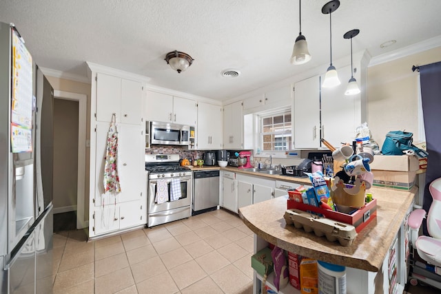 23114 Laura, New Caney, TX 77357 - kitchen featuring appliances with stainless steel finishes, a sink, ornamental molding, a peninsula, and white cabinets