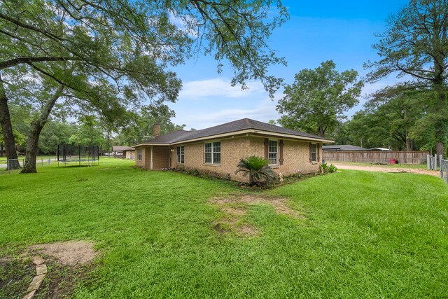 23114 Laura, New Caney, TX 77357 - view of side of property with a trampoline, a chimney, and brick siding