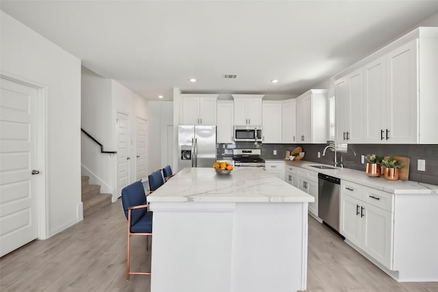 21806 Ash Cypress Ct, Cypress, TX 77433 - kitchen featuring stainless steel appliances, a sink, backsplash, a breakfast bar, and light wood-style floors