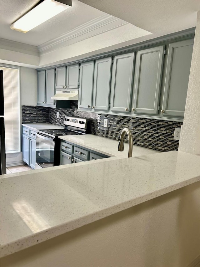 8702 Victorian Village Dr Unit 8702, Houston, TX 77071 - kitchen with under cabinet range hood, stainless steel electric range, tasteful backsplash, gray cabinetry, and ornamental molding