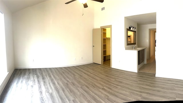 8702 Victorian Village Dr Unit 8702, Houston, TX 77071 - unfurnished living room featuring a ceiling fan, light wood-type flooring, a sink, a towering ceiling, and baseboards