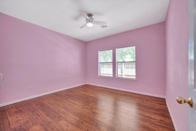 spare room featuring baseboards, wood finished floors, and ceiling fan
