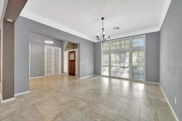 spare room with a chandelier, baseboards, and french doors