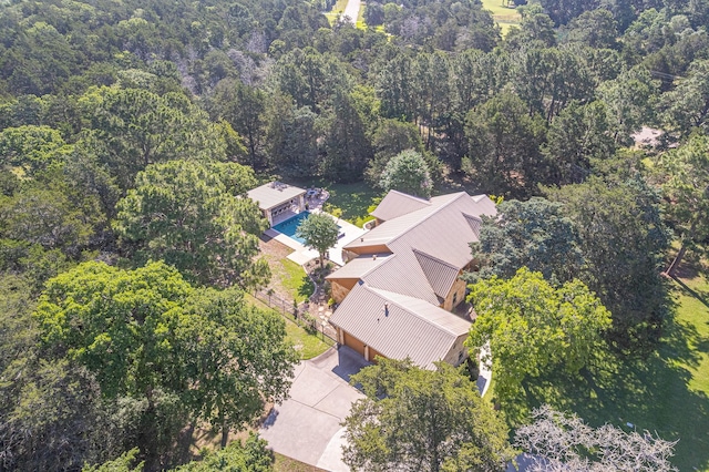 aerial view of property and surrounding area with a forest and a pool area