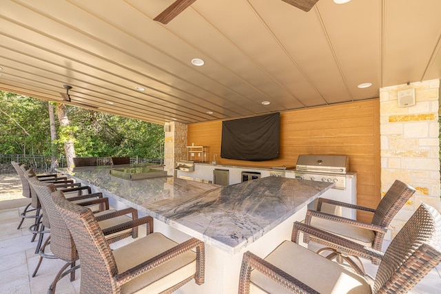 view of patio with exterior kitchen, fence, a grill, and wine cooler