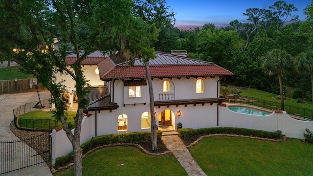 mediterranean / spanish-style house featuring a tile roof, stucco siding, and a chimney