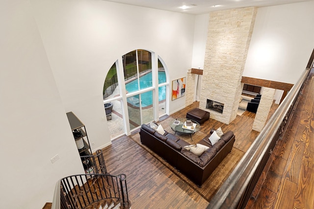 living room featuring wood finished floors, a fireplace, and a high ceiling