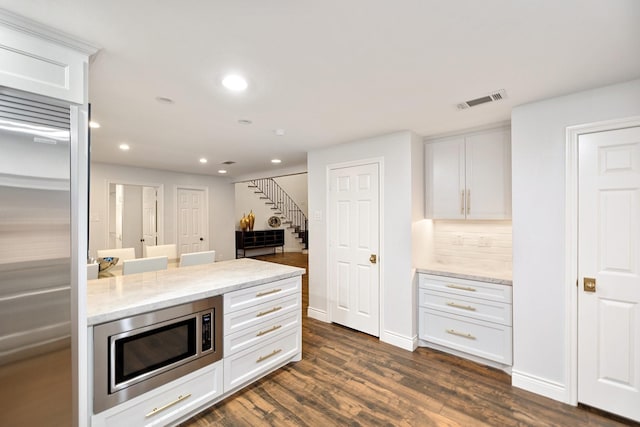 kitchen featuring built in appliances, recessed lighting, light stone countertops, dark wood-style floors, and white cabinetry