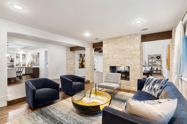 living area with wood finished floors, a stone fireplace, baseboards, and recessed lighting
