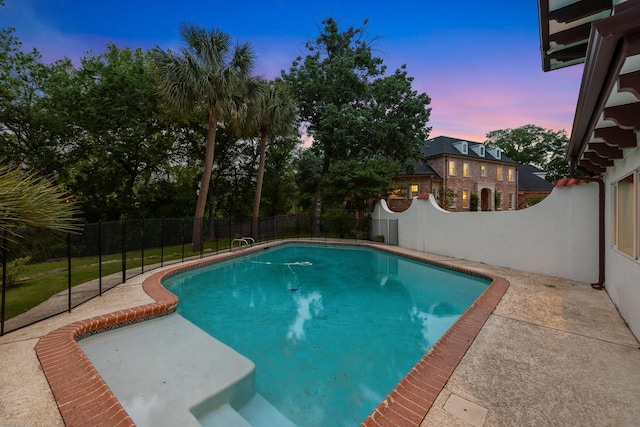 pool at dusk featuring a fenced backyard and a patio area