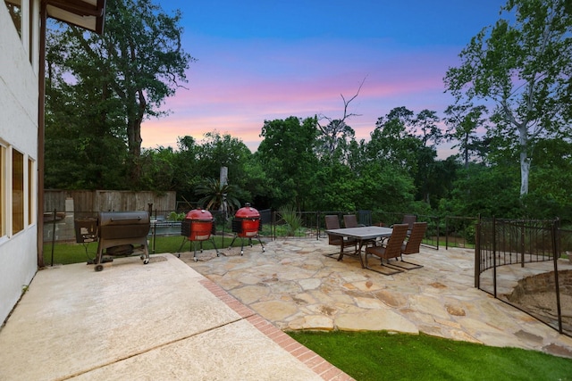 patio terrace at dusk with outdoor dining space and fence