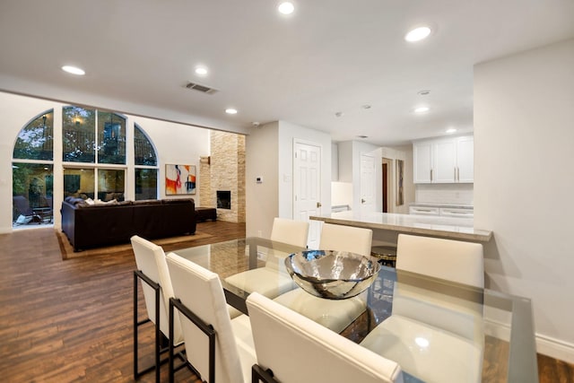 dining area featuring dark wood finished floors, recessed lighting, and a stone fireplace