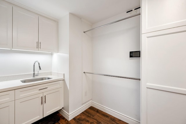 clothes washing area featuring a sink, dark wood-style flooring, and baseboards
