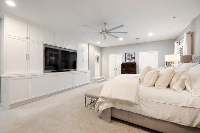 bedroom featuring light colored carpet, recessed lighting, multiple closets, and a ceiling fan