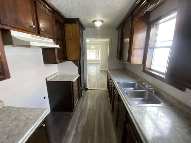 7015 Boyce St, Houston, TX 77020 - kitchen with under cabinet range hood, a sink, dark wood-type flooring, light countertops, and a textured ceiling