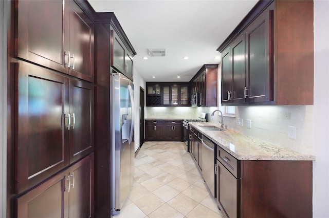 5418 Poinciana Dr, Houston, TX 77092 - kitchen with a sink, appliances with stainless steel finishes, light stone countertops, tasteful backsplash, and glass insert cabinets