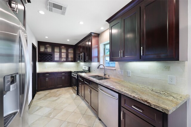 5418 Poinciana Dr, Houston, TX 77092 - kitchen featuring appliances with stainless steel finishes, a sink, tasteful backsplash, light stone countertops, and glass insert cabinets