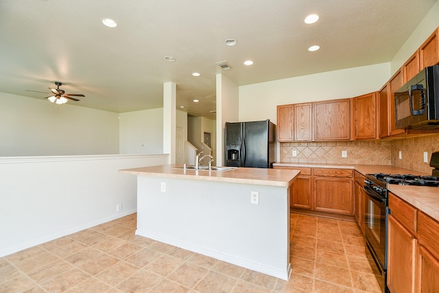 kitchen featuring black appliances, light countertops, backsplash, recessed lighting, and a center island with sink