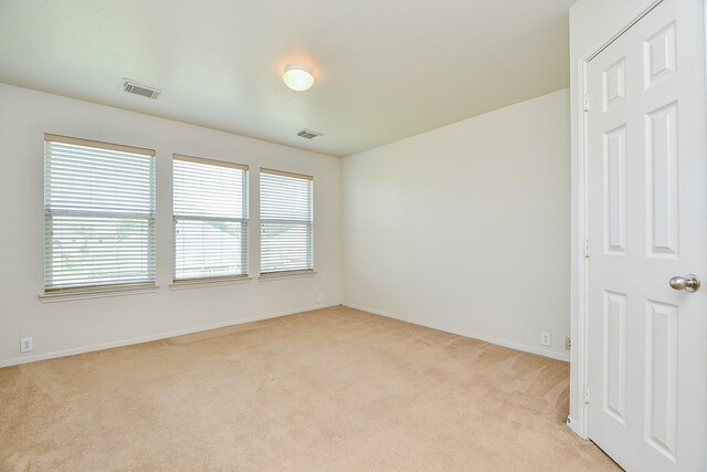 unfurnished room featuring light colored carpet, healthy amount of natural light, and baseboards