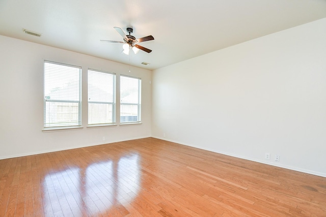 spare room with a ceiling fan, light wood finished floors, and baseboards