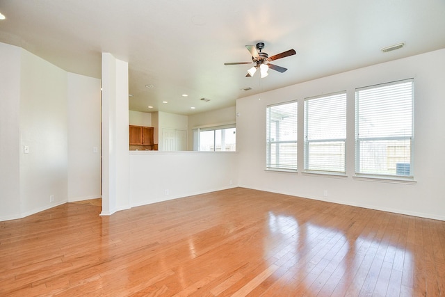 unfurnished living room featuring ceiling fan, light wood-style flooring, and baseboards