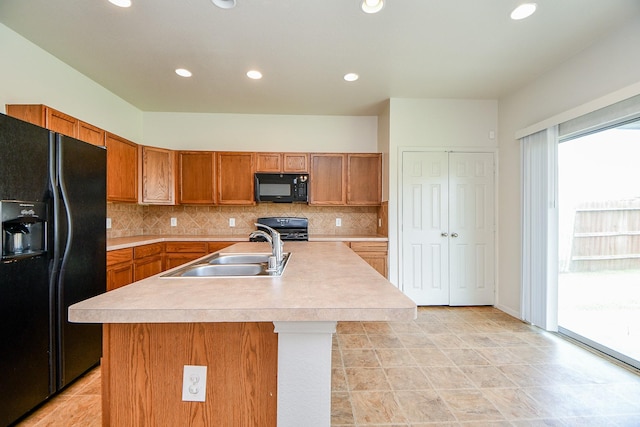 kitchen featuring black appliances, a sink, light countertops, brown cabinetry, and tasteful backsplash