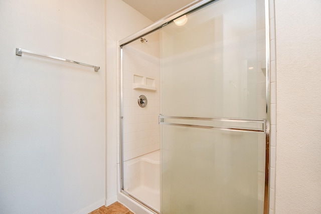 bathroom with a stall shower and baseboards