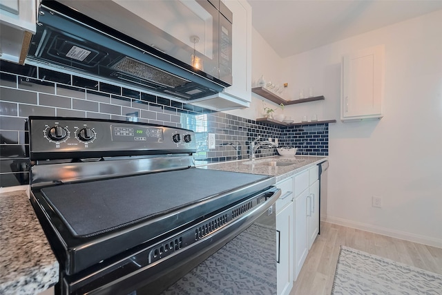 kitchen with black electric range oven, a sink, white cabinets, decorative backsplash, and light wood-style floors
