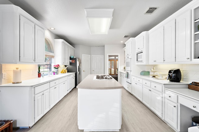 kitchen with white appliances, white cabinetry, backsplash, and recessed lighting