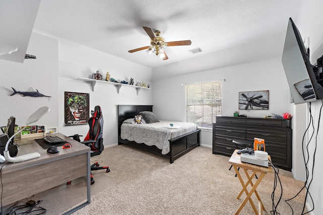 bedroom featuring light colored carpet, baseboards, an office area, a textured ceiling, and a ceiling fan