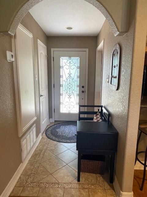 52 April Hl Unit 52, Conroe, TX 77356 - entryway featuring light tile patterned floors, arched walkways, baseboards, a textured wall, and inlaid floor details