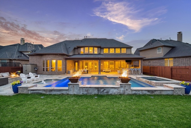2011 Greenvine Cir, Katy, TX 77494 - back of property featuring a fire pit, an in-ground hot tub, a patio area, brick siding, and roof with shingles