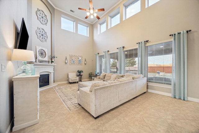 2011 Greenvine Cir, Katy, TX 77494 - living room with ornamental molding, a glass covered fireplace, ceiling fan, light tile patterned floors, and a high ceiling