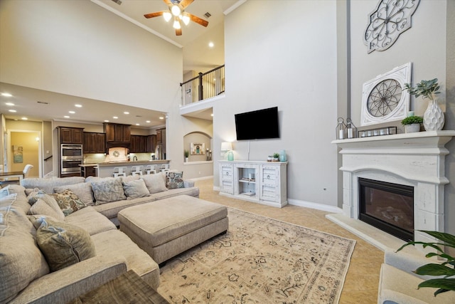 2011 Greenvine Cir, Katy, TX 77494 - living room with a ceiling fan, a towering ceiling, a glass covered fireplace, light tile patterned flooring, and baseboards