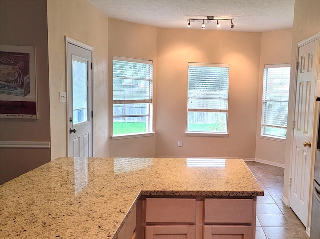 kitchen with plenty of natural light, light stone countertops, light tile patterned floors, and a textured ceiling