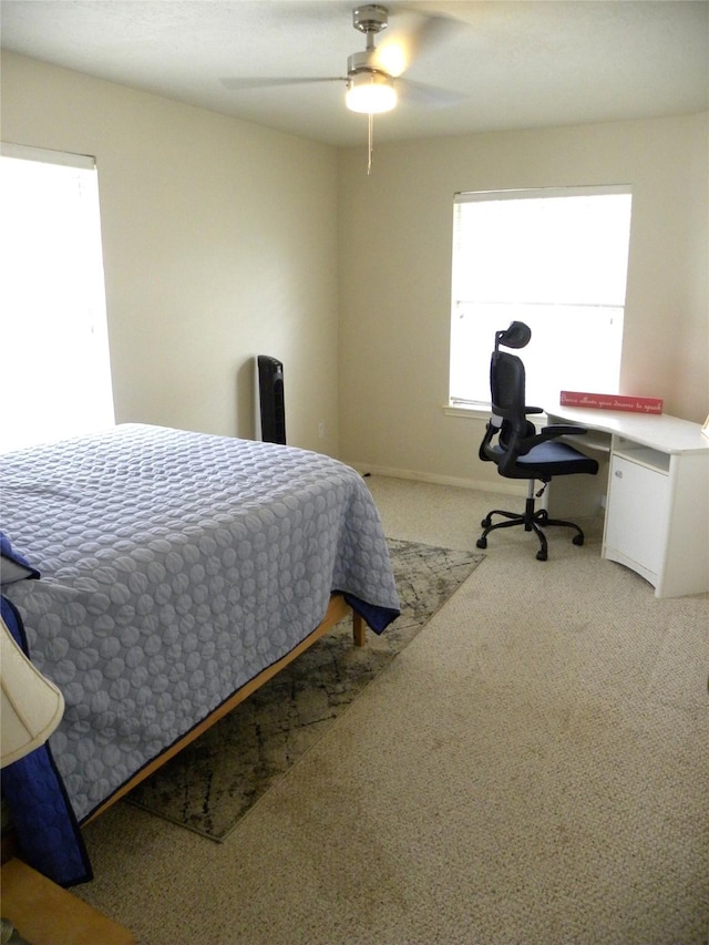 bedroom with light carpet, an office area, and a ceiling fan