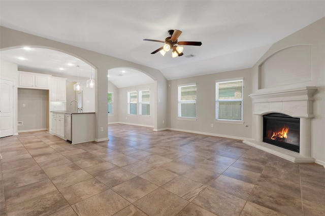 19219 S Cottonwood Green Ln, Cypress, TX 77433 - unfurnished living room featuring a sink, a ceiling fan, a glass covered fireplace, healthy amount of natural light, and lofted ceiling