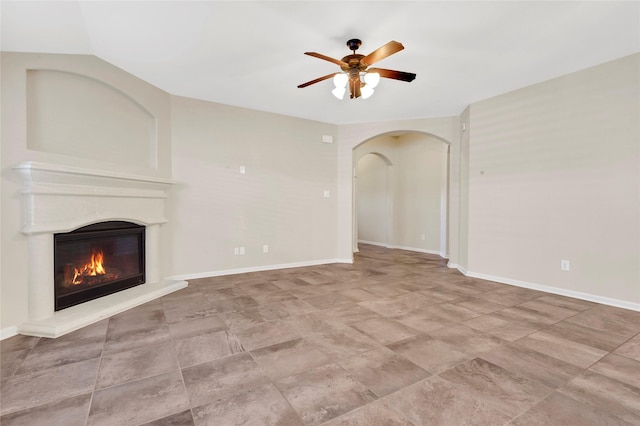 19219 S Cottonwood Green Ln, Cypress, TX 77433 - unfurnished living room featuring a glass covered fireplace, a ceiling fan, arched walkways, and baseboards