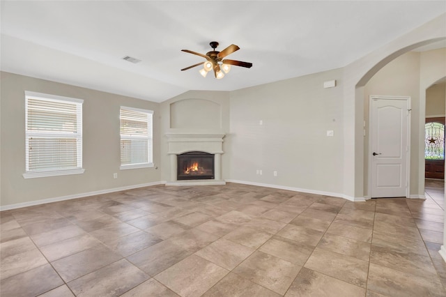 19219 S Cottonwood Green Ln, Cypress, TX 77433 - unfurnished living room with ceiling fan, arched walkways, plenty of natural light, a glass covered fireplace, and vaulted ceiling