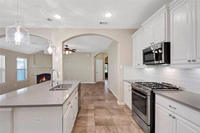 19219 S Cottonwood Green Ln, Cypress, TX 77433 - kitchen featuring appliances with stainless steel finishes, a sink, tasteful backsplash, a warm lit fireplace, and ceiling fan