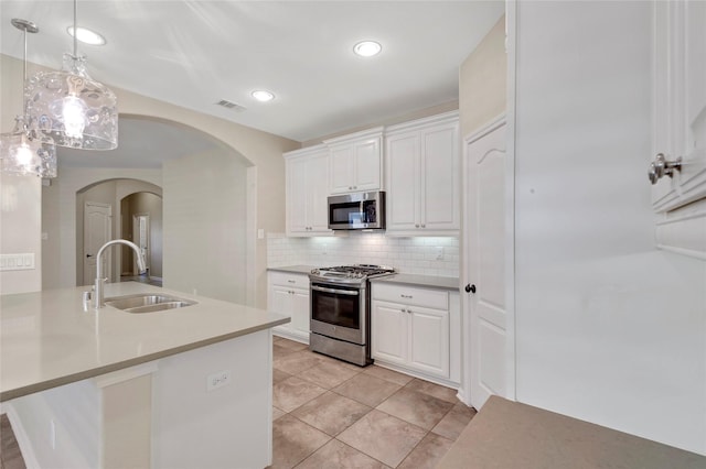 19219 S Cottonwood Green Ln, Cypress, TX 77433 - kitchen with stainless steel appliances, a sink, arched walkways, white cabinetry, and tasteful backsplash