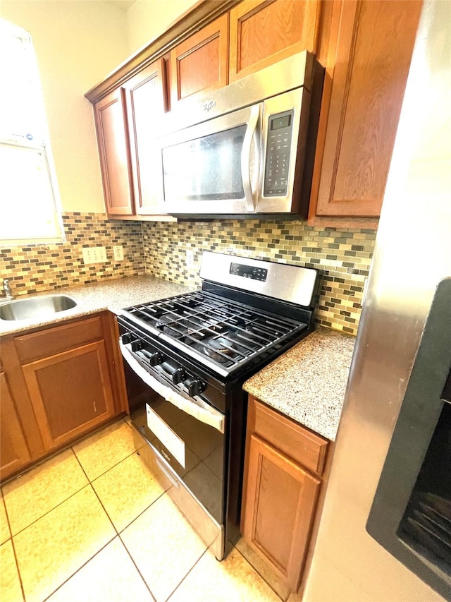 13150 Lawsons Creek Ln, Houston, TX 77072 - kitchen with stainless steel appliances, a sink, backsplash, light tile patterned floors, and brown cabinetry