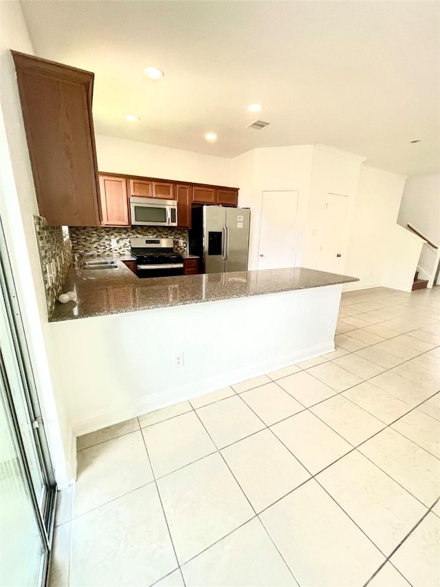 13150 Lawsons Creek Ln, Houston, TX 77072 - kitchen featuring appliances with stainless steel finishes, dark stone counters, light tile patterned flooring, a peninsula, and recessed lighting
