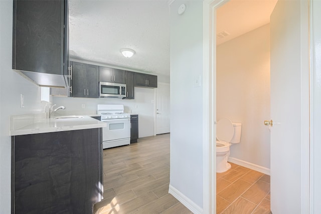 20101 Dawn Mist Dr, Humble, TX 77346 - kitchen featuring white gas stove, stainless steel microwave, light countertops, baseboards, and wood tiled floors