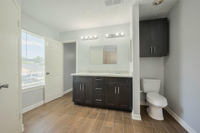 20101 Dawn Mist Dr, Humble, TX 77346 - full bathroom featuring wood tiled floors, baseboards, toilet, double vanity, and a textured ceiling