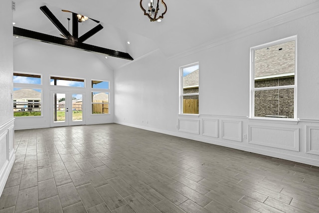 318 Little Spring Ct, Anahuac, TX 77523 - unfurnished living room featuring a chandelier, plenty of natural light, beam ceiling, wood finished floors, and high vaulted ceiling