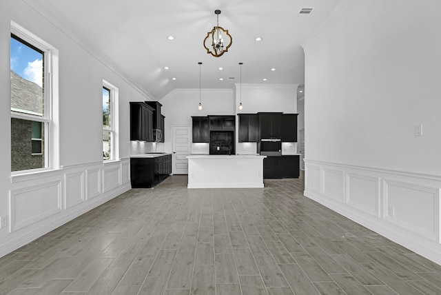 318 Little Spring Ct, Anahuac, TX 77523 - kitchen featuring a chandelier, crown molding, dark cabinetry, a wainscoted wall, and a center island