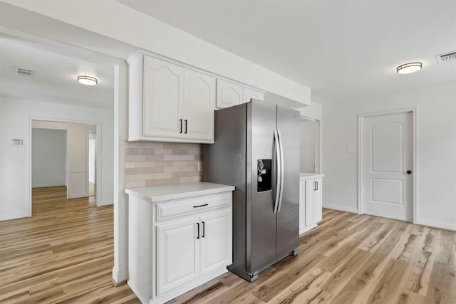 2407 Del Norte St, Houston, TX 77018 - kitchen featuring stainless steel refrigerator with ice dispenser, light wood-style flooring, light countertops, white cabinetry, and decorative backsplash