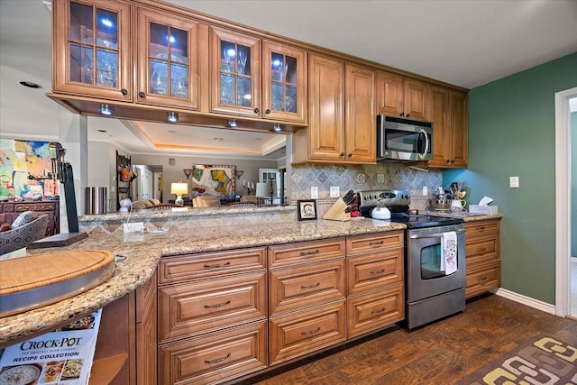12392 Fm 355, Trinity, TX 75862 - kitchen featuring appliances with stainless steel finishes, brown cabinetry, dark wood-type flooring, and light stone counters