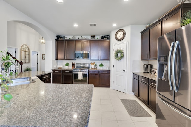 8619 Morning Dove Ln, Baytown, TX 77521 - kitchen with stainless steel appliances, arched walkways, a sink, dark brown cabinets, and recessed lighting